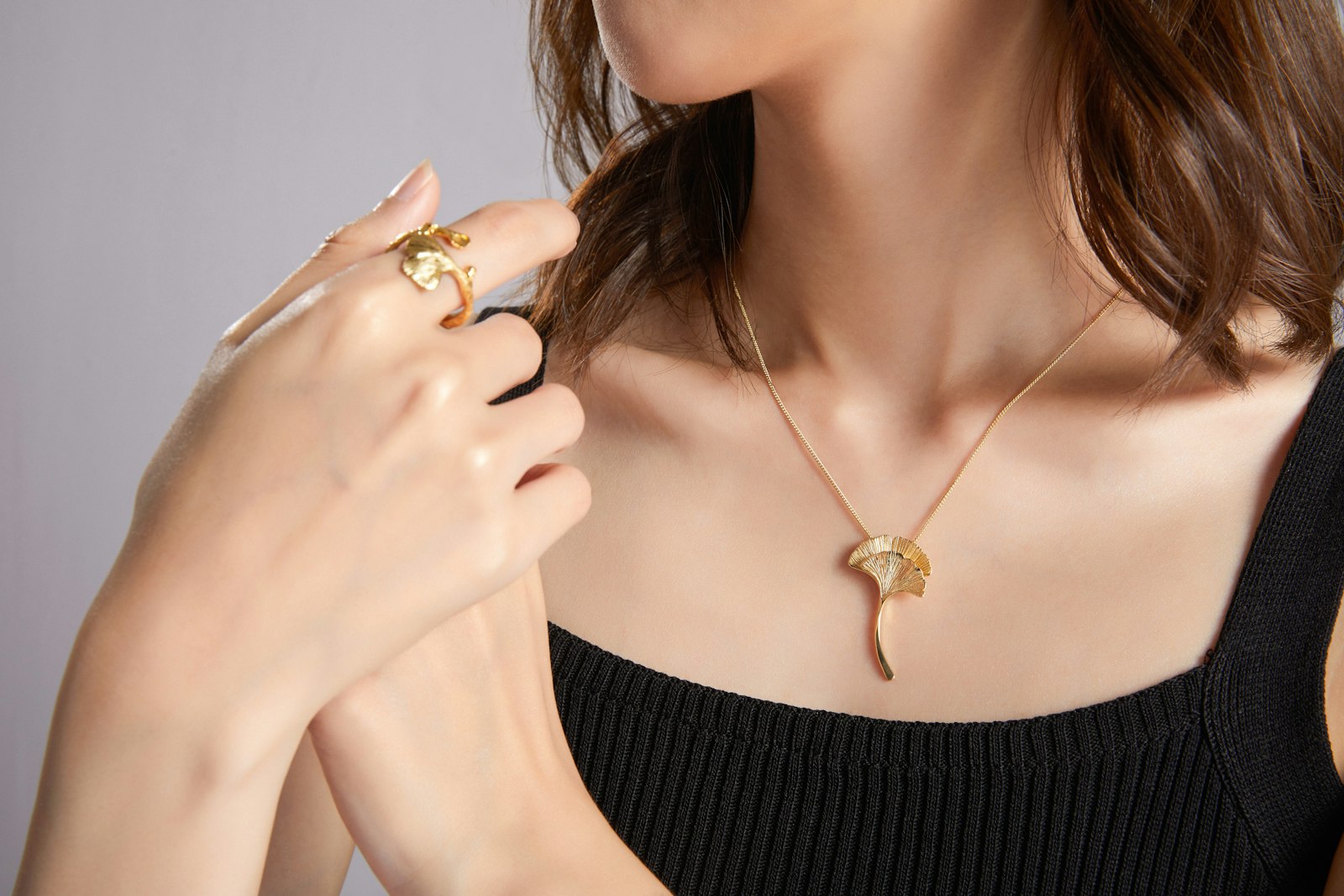Woman wearing a gold leaf pendant necklace and ring