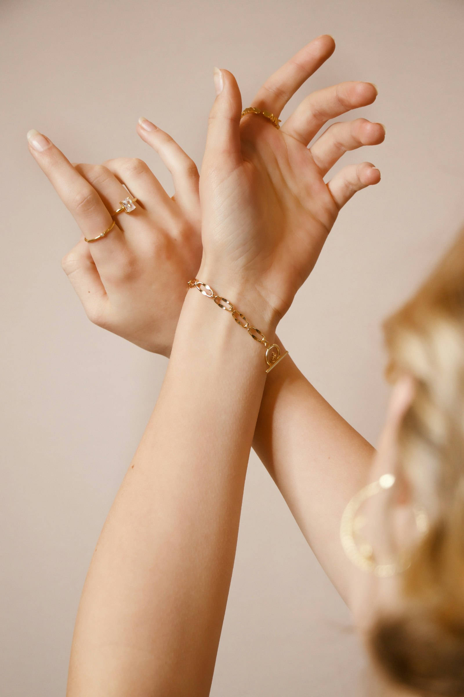 Hands wearing gold rings and a gold chain bracelet