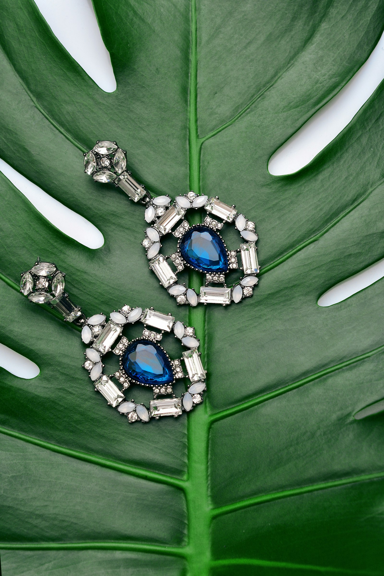 Blue crystal statement drop earrings on a green leaf