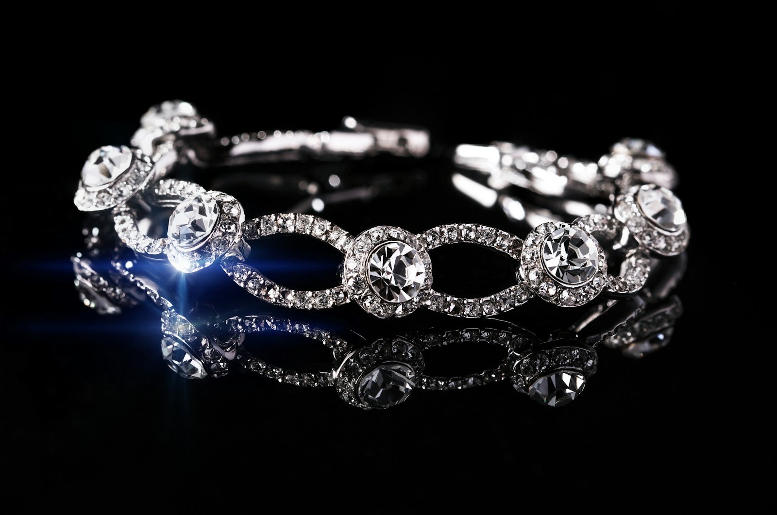 Crystal-set silver bracelet reflected on a black surface