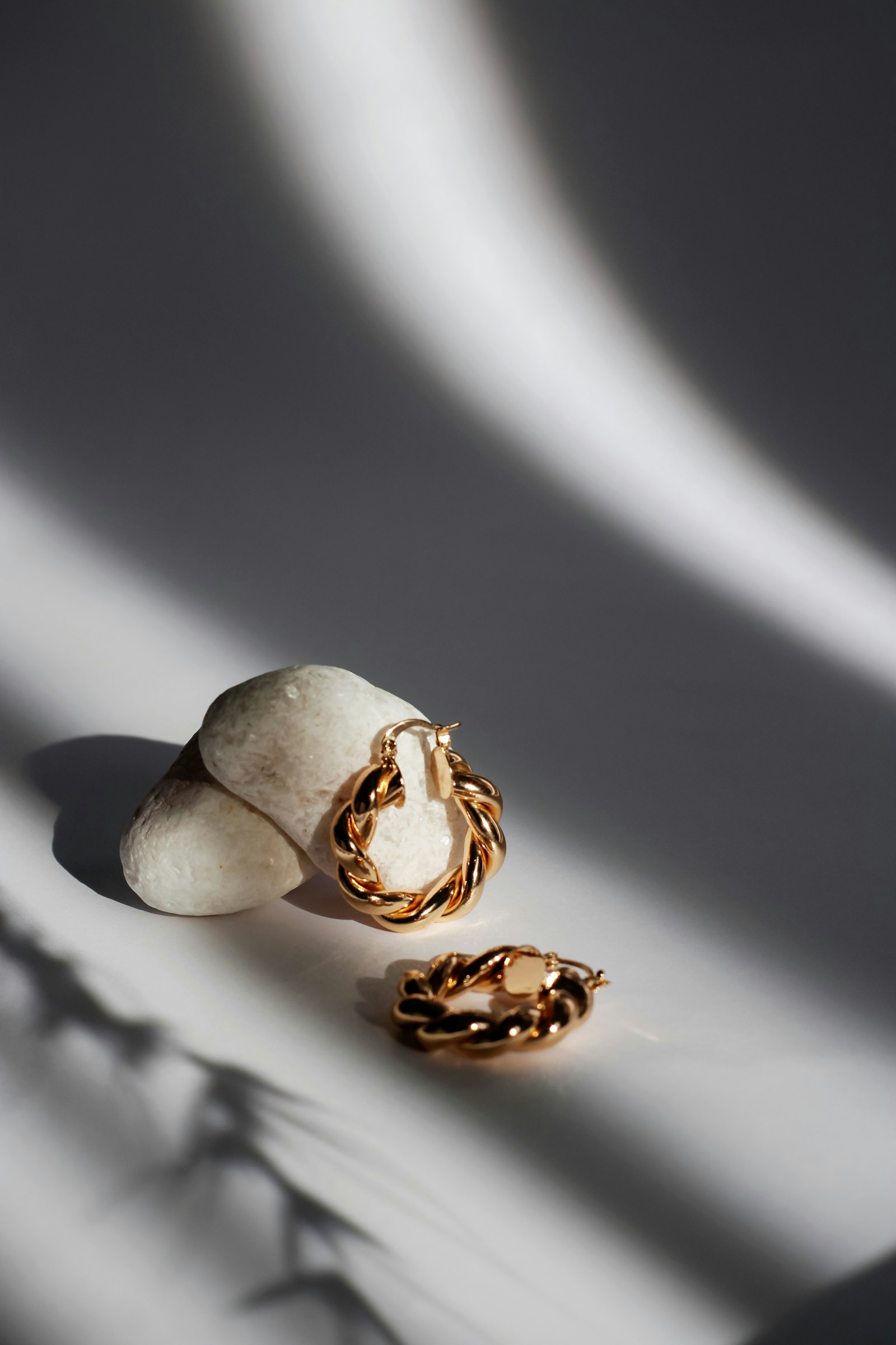 Gold twisted hoop earrings resting in soft sunlight